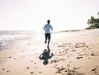 Unrecognizable man running on sandy beach